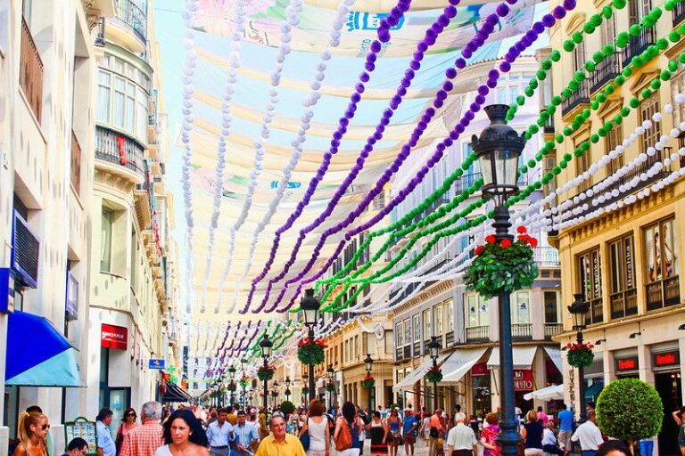 A view of a street with people and coloured ribbons above