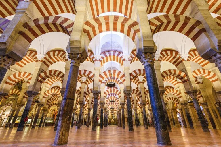 A room filled with arabic pillars and red and cream coloured arches